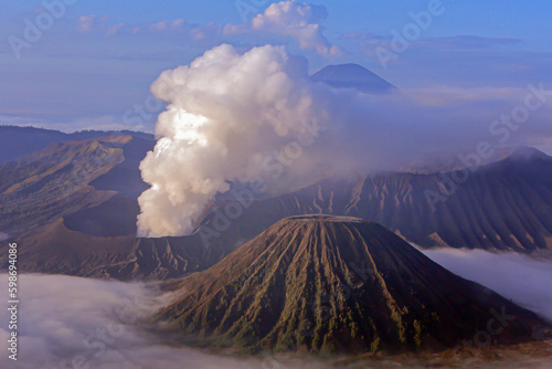 Mount Bromo emits sulfuric smoke at sunrise with a backdrop of Mount Semeru in the Bromo Tengger Semeru National Park, East Java, Indonesia.