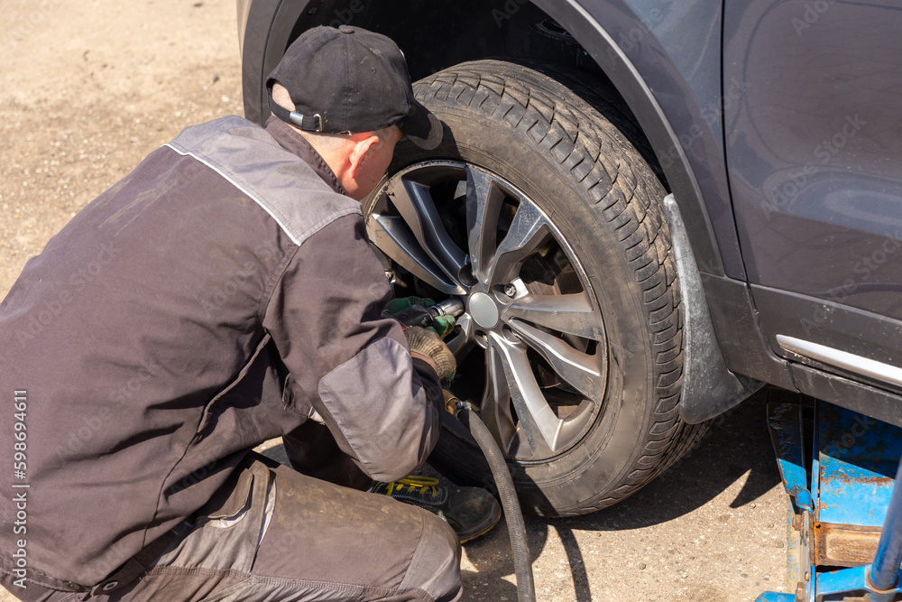 Mechanician changing car wheel in auto repair shop. Mechanician changing car wheel in auto repair shop.