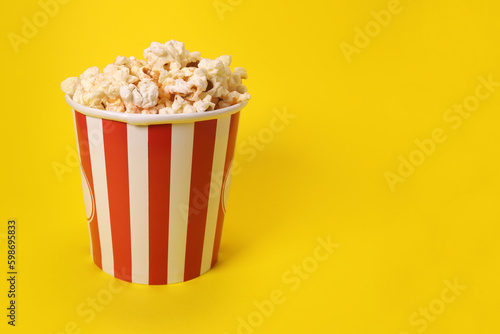 Paper cup with popcorn on yellow background. copy space for text