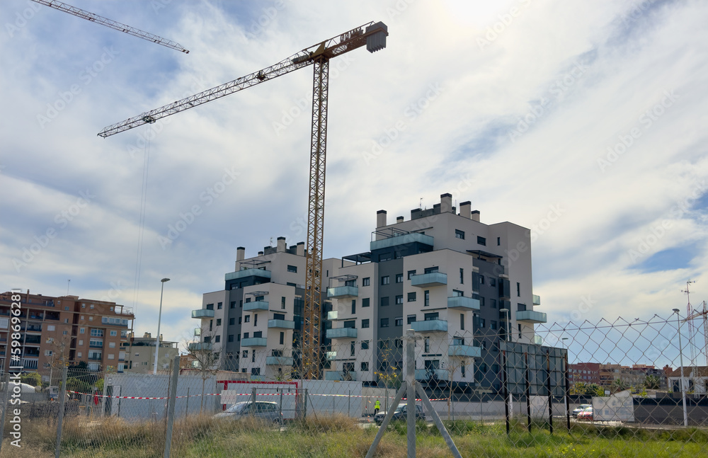 Towhouse under construction. Tower crane on construction site.  construction near Mediterranean sea. Construction of modern house on coastline, Spain, Sagunto. Home renovation. Build new home.