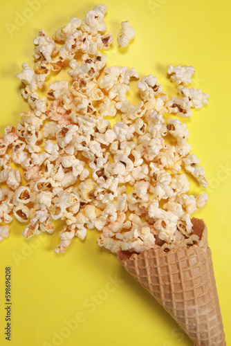 Sweet caramel popcorn in a waffle cup of ice cream on a yellow background. Vertical Orientation