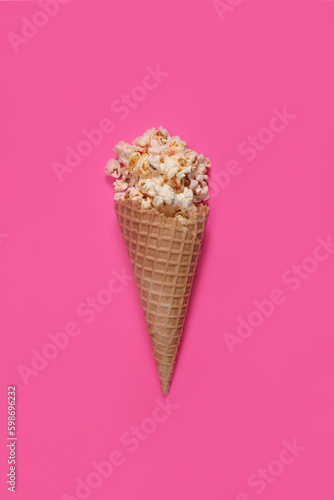 Sweet caramel popcorn in ice cream waffle cup on pink background. Vertical Orientation