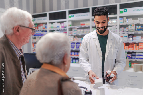 Young pharmacist selling medications to senior couple. © Halfpoint