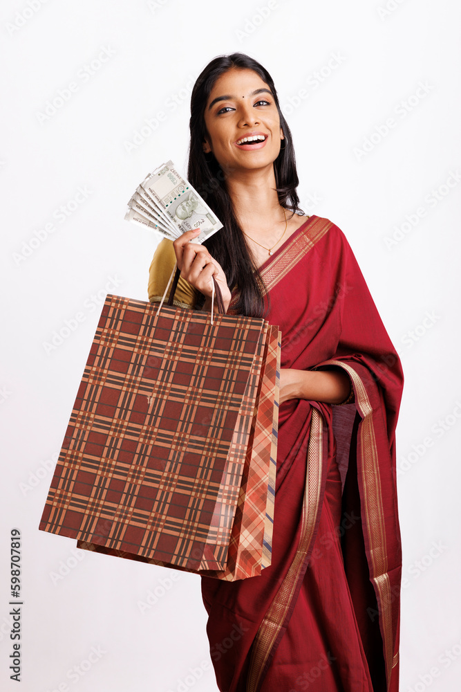 Surprised South Indian woman in traditional saree and holding shopping bags with Indian currency isolated on white. Surprised South Indian woman in traditional saree and holding shopping bags with Indian currency isolated on white.