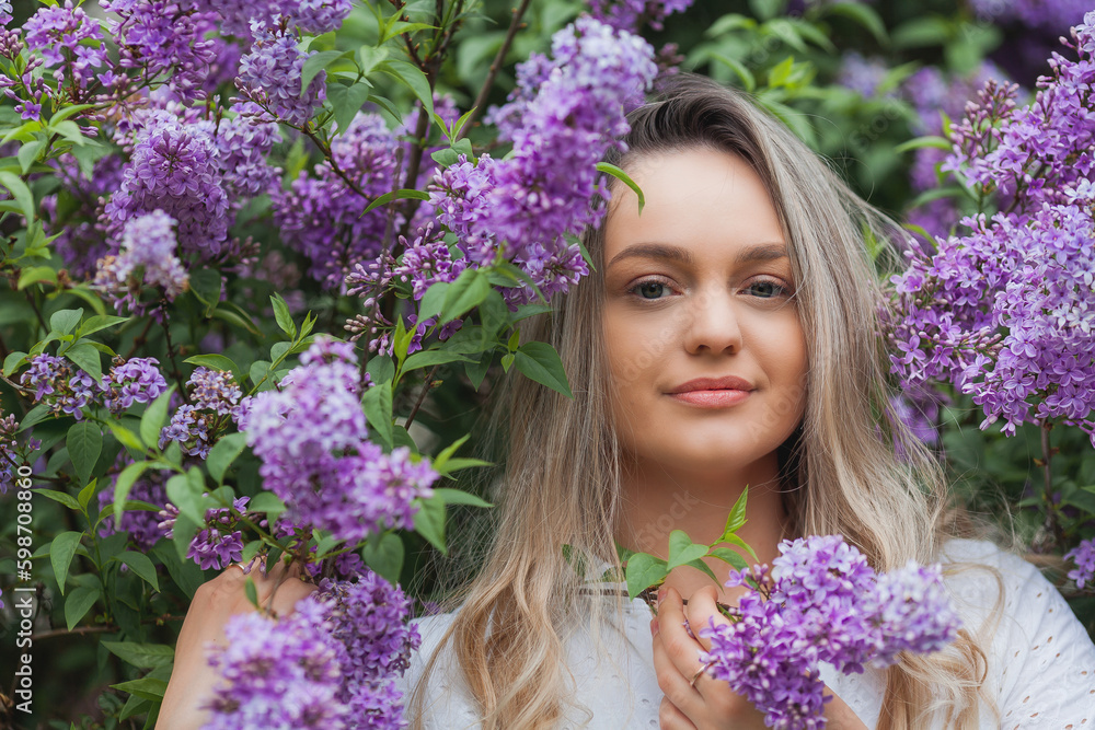 Portrait of beautiful young blue-eyed blonde woman near blooming lilac. Spring. Portrait of beautiful young blue-eyed blonde woman near blooming lilac. Spring.