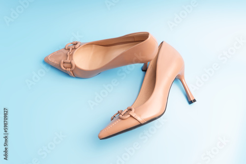 A pair of elegant beige women's shoes on a blue background