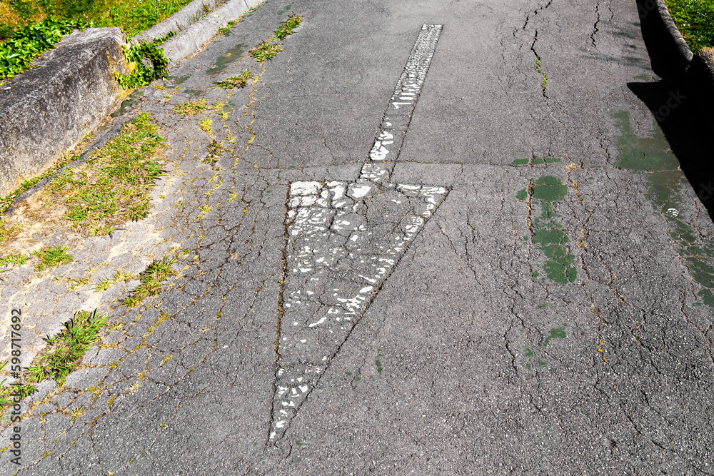 Fototapeta premium Reverse direction arrow on a weathered asphalt road