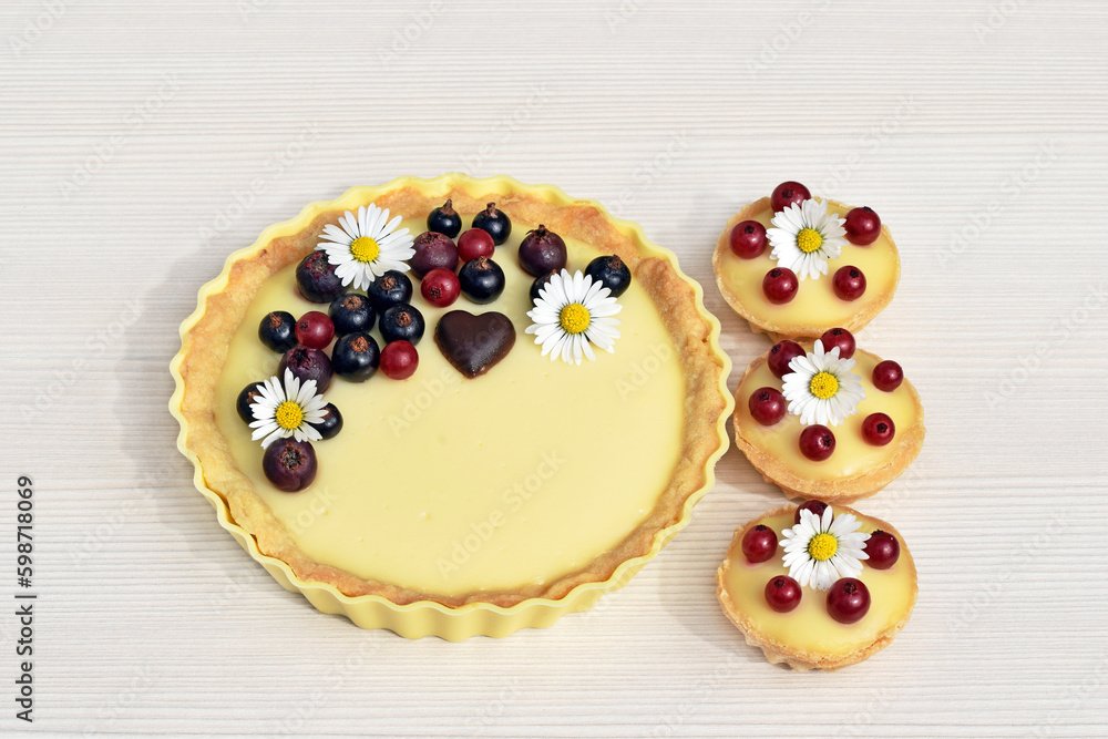 Shortbread vanilla tartlets with fruits, chocolate heart and edible daisy flowers, light background Shortbread vanilla tartlets with fruits, chocolate heart and edible daisy flowers, light background