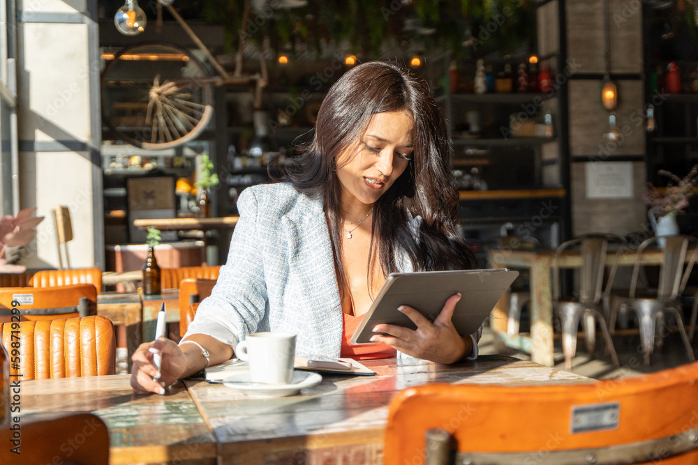 Shocked woman looking with surprise at the digital tablet while sitting in a coffee shop. Shocked woman looking with surprise at the digital tablet while sitting in a coffee shop.