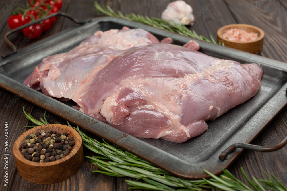 Turkey thigh meat raw on a tray with herbs and spices