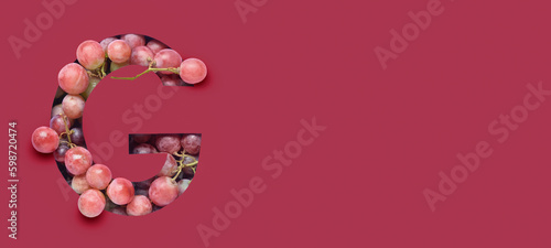 Letter G cut in viva magenta paper and ripe grapes. Banner for design photo