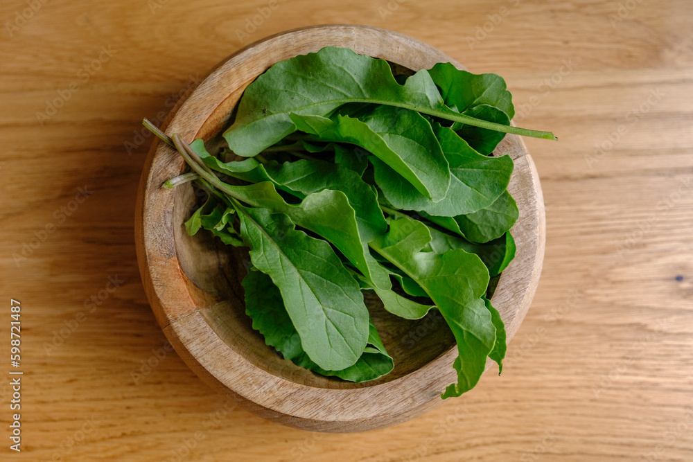 close up of arugula in a bowl with a walnut wood background close up of arugula in a bowl with a walnut wood background