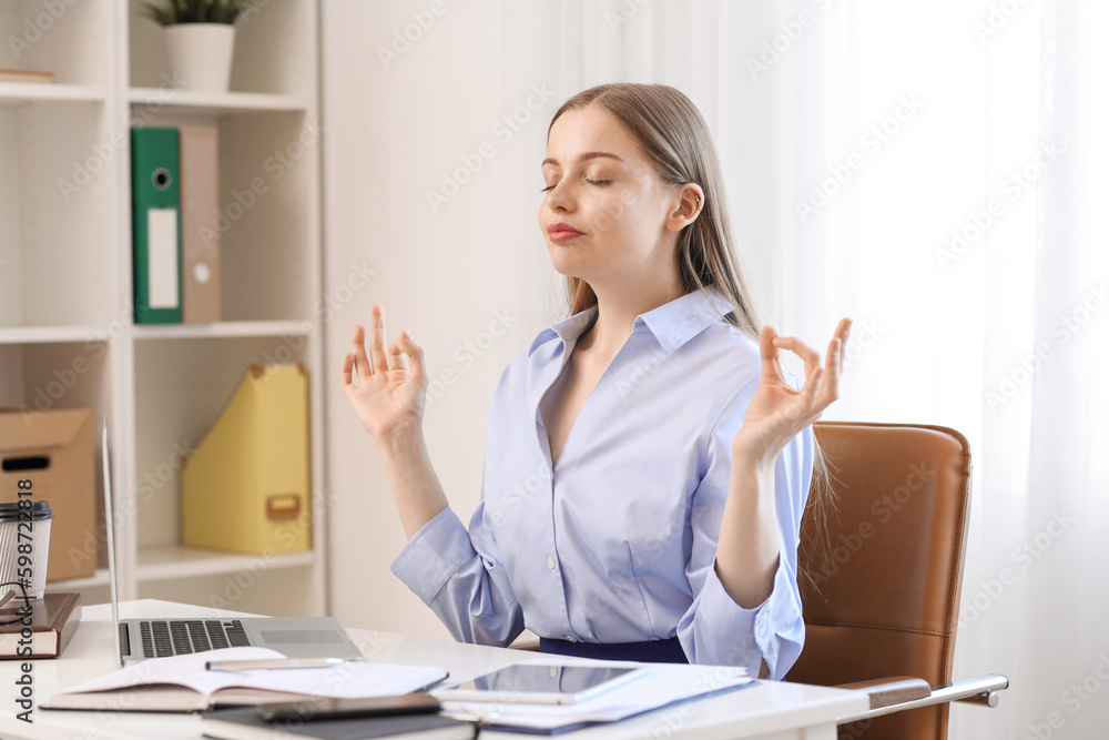 Young businesswoman meditating in office. Balance concept Young businesswoman meditating in office. Balance concept