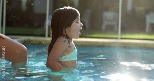 Girl splashing water at swimming pool during summer day