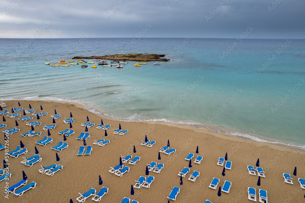 Drone aerial of beach chairs in a  tropical sandy beach. Summer holidays in the sea. Protaras Cyprus Europe