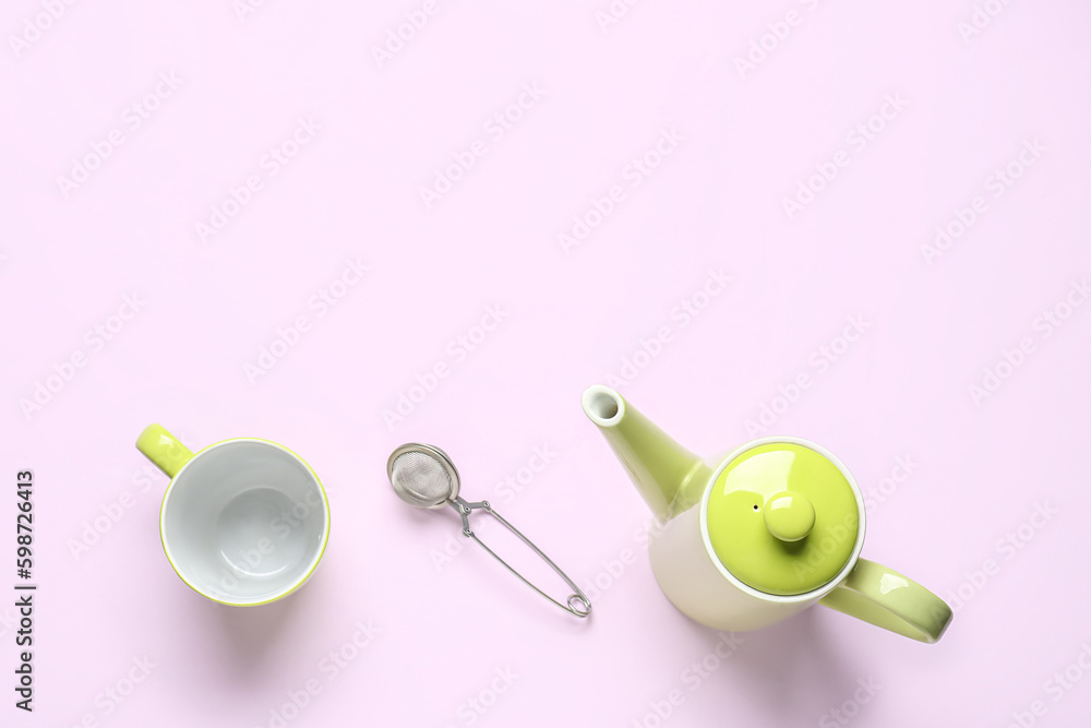 Teapot, mug and infuser on lilac background Teapot, mug and infuser on lilac background