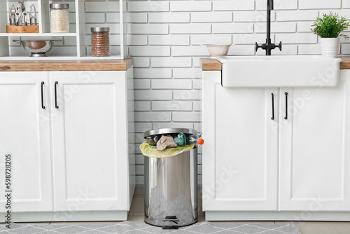 Full trash bin in interior of modern kitchen