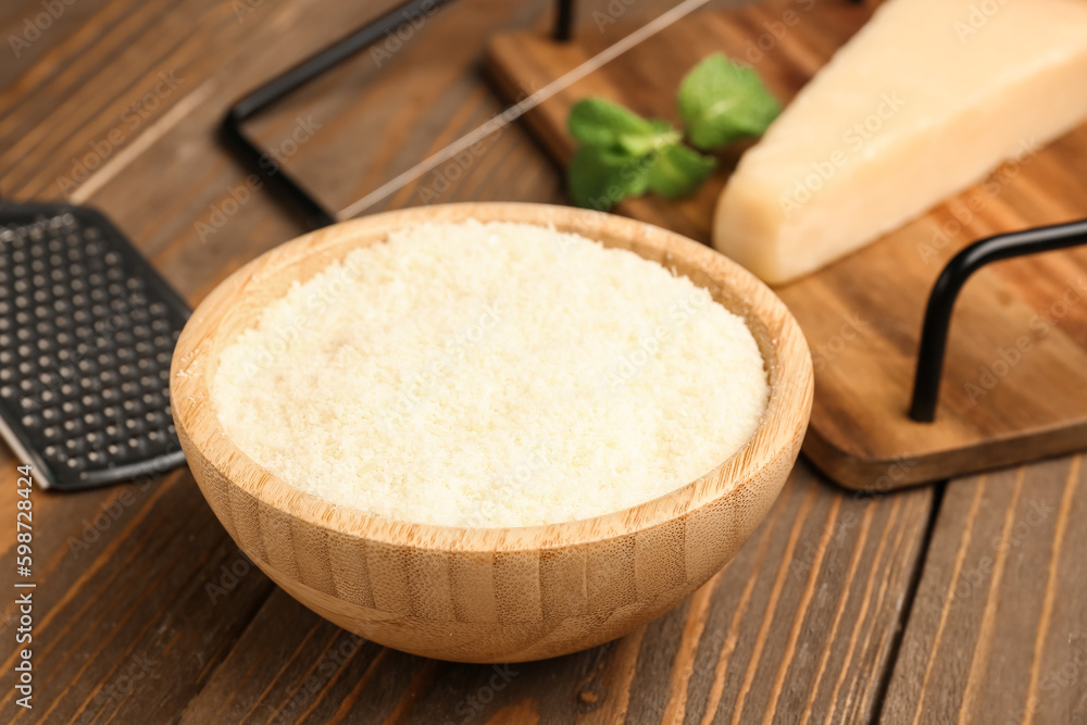 Bowl with tasty grated Parmesan cheese on wooden background, closeup Bowl with tasty grated Parmesan cheese on wooden background, closeup
