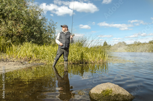 Fisherman throws spinning while standing in the water.