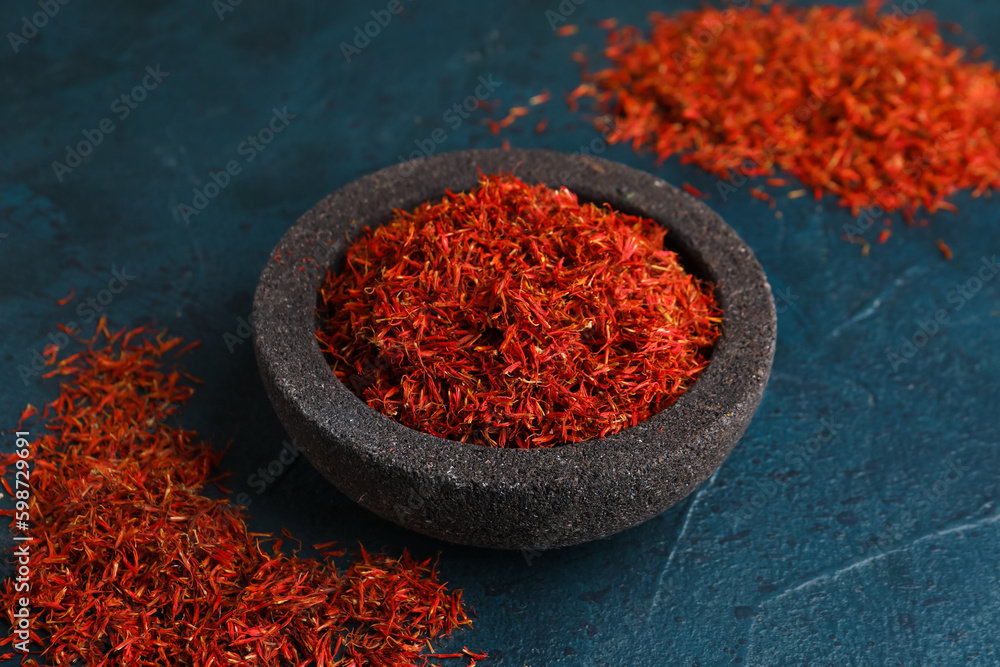 Bowl with pile of saffron on dark grunge background Bowl with pile of saffron on dark grunge background