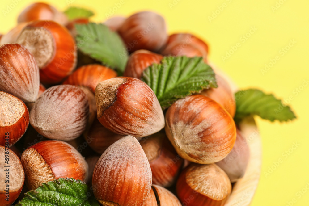 Shelled hazelnuts with leaves on yellow background, closeup Shelled hazelnuts with leaves on yellow background, closeup