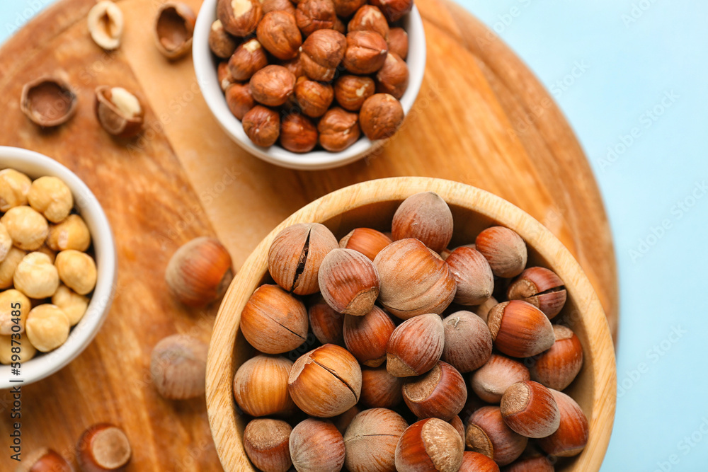 Board and bowls with hazelnuts on blue background Board and bowls with hazelnuts on blue background