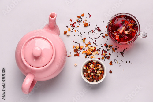 Foto Ceramic teapot with cup of tea and dried fruits on grey background