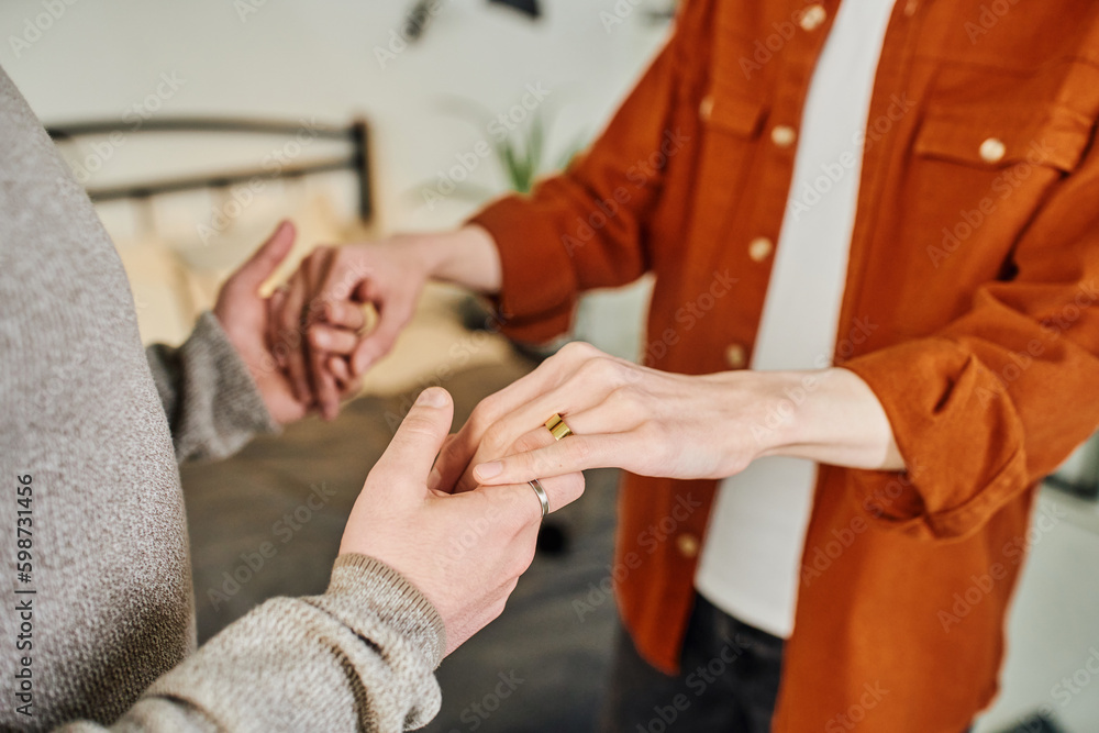 partial view of gay man holding hands of boyfriend in wedding ring in bedroom. partial view of gay man holding hands of boyfriend in wedding ring in bedroom.