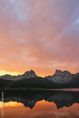 Golden sunset in mountain lake. Two peaks reflected in water