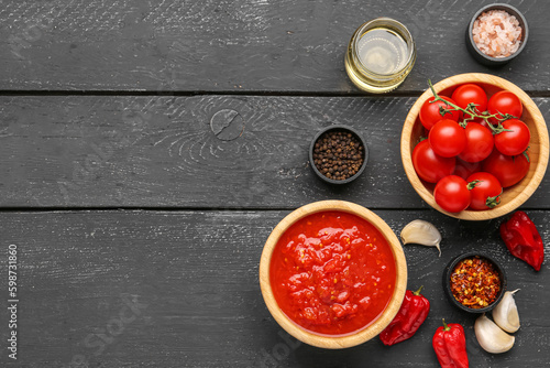 Bowls with tasty tomato sauce and ingredients on dark wooden background