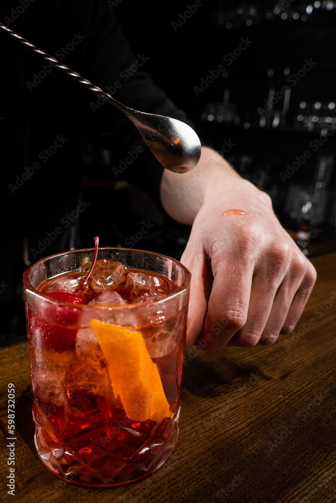 Bartender puts a drop of Negroni alcoholic cocktail on his hand and tastes it. Barman prepares classical Negroni cocktail at the bar. Bartender puts a drop of Negroni alcoholic cocktail on his hand and tastes it. Barman prepares classical Negroni cocktail at the bar.
