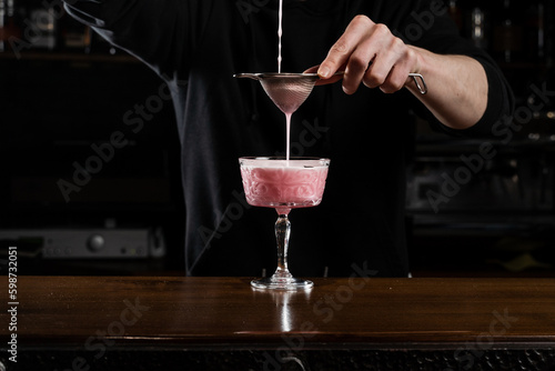 Foto Bartender is pouring pink Clover club alcoholic cocktail in the glass