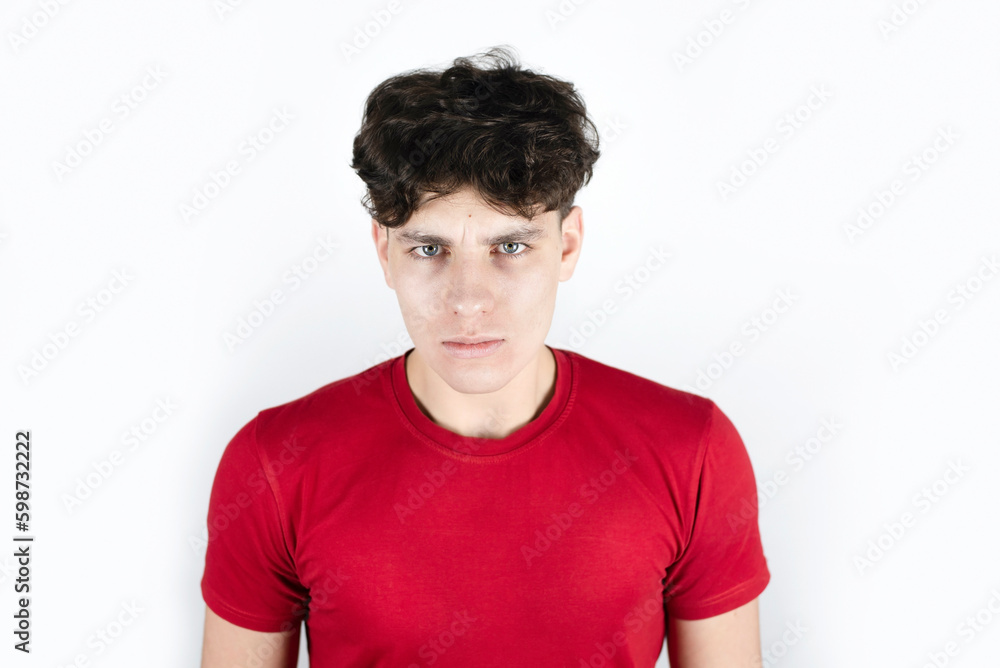 Fototapeta premium A young guy of 18 years old with a disappointed face, sad, negative emotions and a headache from stress at college and at work. The boy learns to combine college studies and work