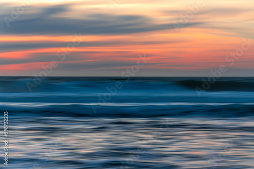 Red sunset over the sea, abstract seascape background in bright red-pink and blue colors, design, motion blur