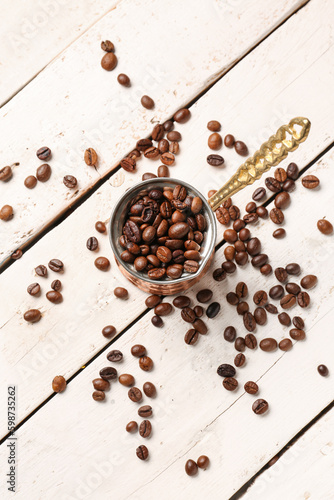 Pot with coffee beans on light wooden background