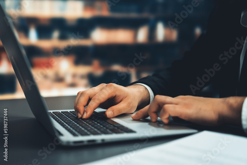 Businessman focused on his laptop working on financial report or planning business strategy in library. Modern office worker utilizing technology in the field of business. Equilibrium Generative AI