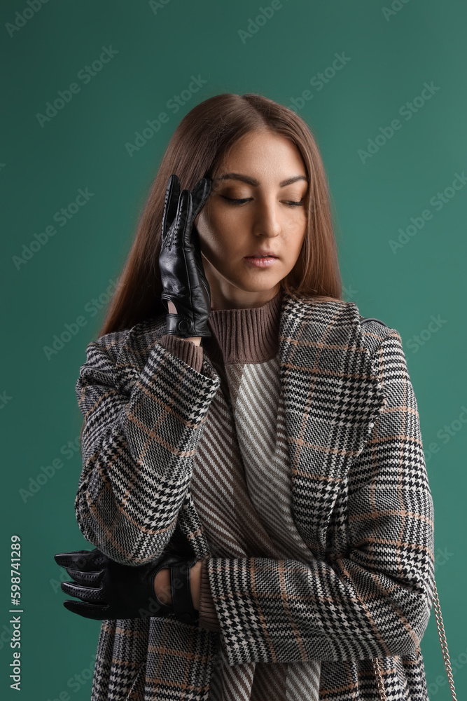 Beautiful young woman in leather gloves and coat on green background Beautiful young woman in leather gloves and coat on green background