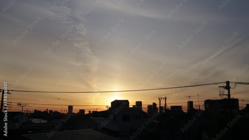 A view of the sunrise in Tokyo. Early morning in a residential area. There are silhouettes of tall sky scrappers at far distances. A view of the sunrise in Tokyo. Early morning in a residential area. There are silhouettes of tall sky scrappers at far distances.