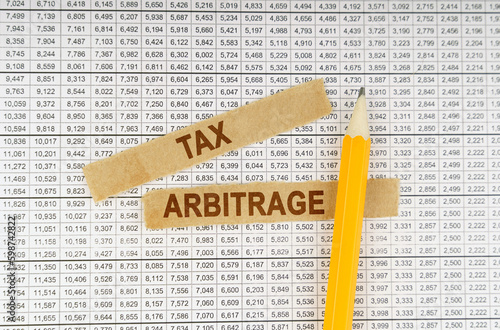 On the documents with reports are a pencil and strips of paper with the inscription - Tax Arbitrage photo