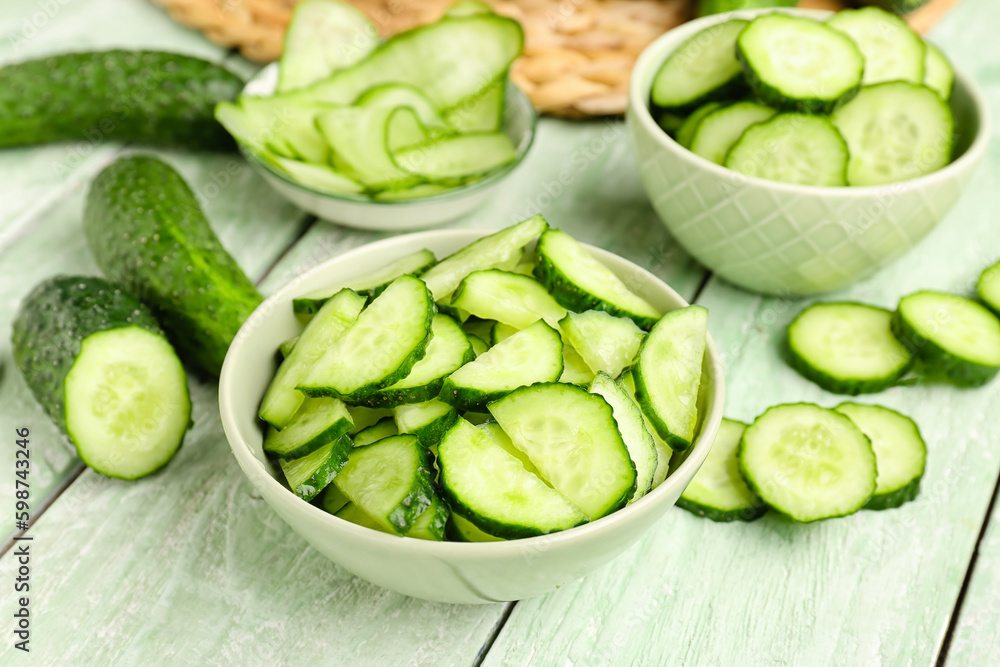 Bowl with pieces of fresh cucumber on light wooden background Bowl with pieces of fresh cucumber on light wooden background