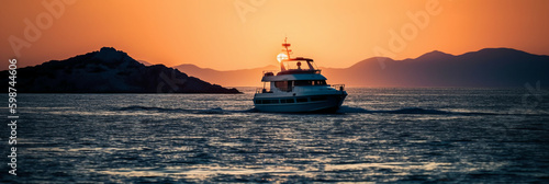 Luxury yacht sailing in the middle of the sea beside an island and mountains in the horizon at sunset as wide banner. AI generative 