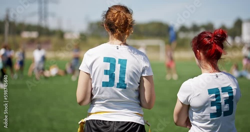 Silhouettes of girls watching the match at the stadium. flag football competitions among female teams. Blue flag flying over the field during the match. Concept of sport and victory photo