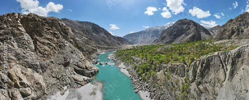 A 180-degree aerial panorama of a valley and a flowing river of green glacial water, located between the surrounding mountains. 