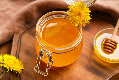 Board with jar of dandelion honey as background  closeup