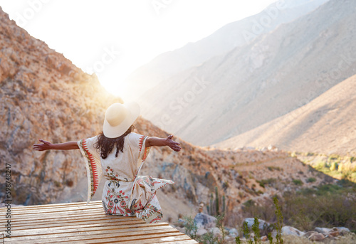 vista trasera mujer sentada con los brazos abiertos en el Valle del Elqui  photo