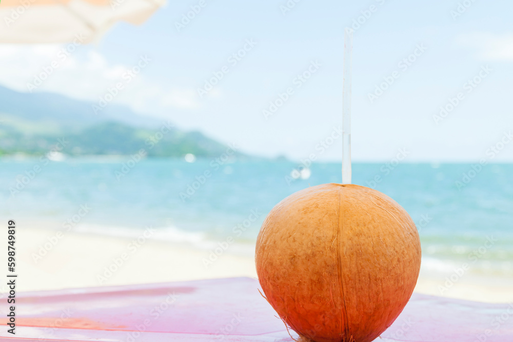 Iced coconut on a beach kiosk table..Brazilian tropical beach in hot summer on Ilhabela. Coconut concept.