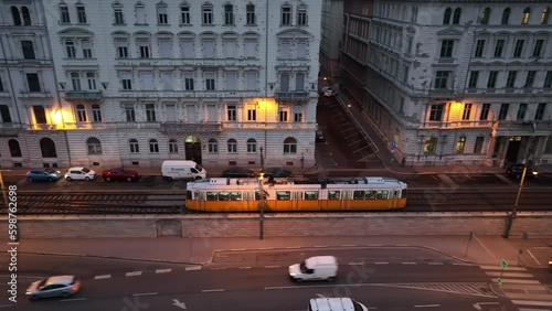 Aerial view of Typical Budapest Tram passing through city neighbourhood during blue hour, Aerial tracking follow shot wide angle, Hungary