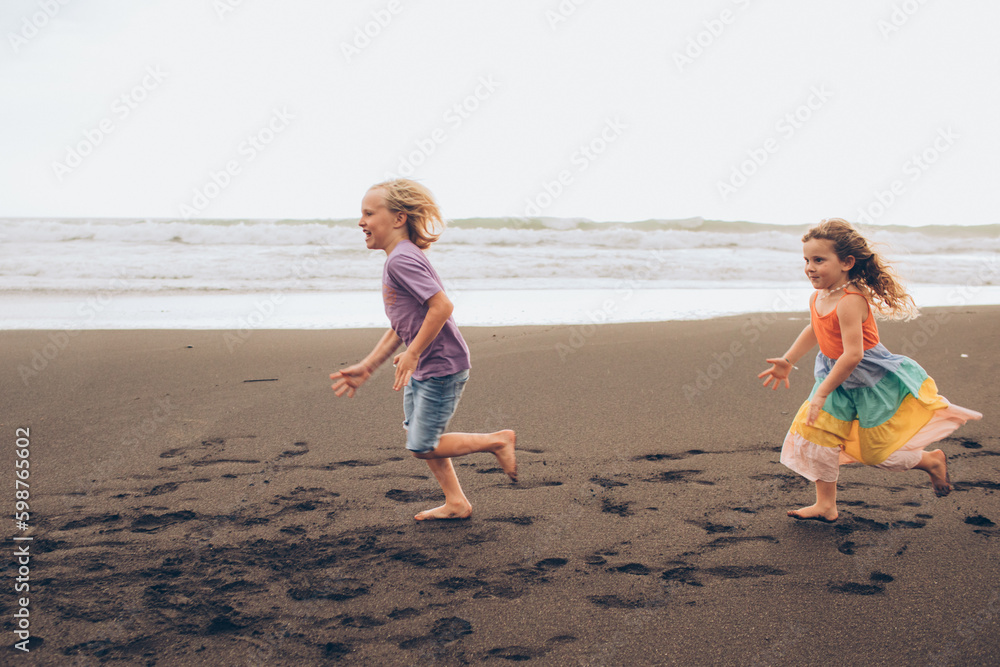 Kids running on the beach with the waves behind them
