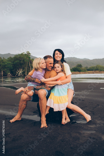 family with small children in colorful clothing hugging on the beach