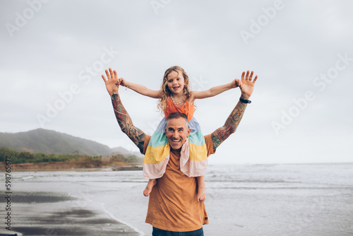 dad with daughter on his shoulders running at the beach